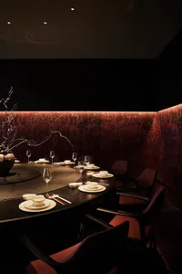 Elegant dining area with a round table, chairs, wine glasses, and table settings, suggesting a sophisticated interior design