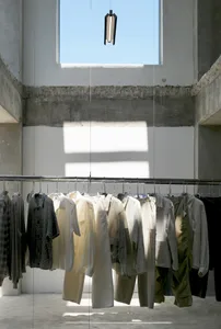 A bright and airy storage space with concrete walls, featuring a large window and hanging clothes