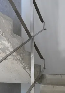 A modern staircase with metal stairs and a concrete wall in a building's interior, suggesting a functional yet stylish design element