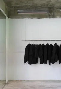 A clean and organized closet with a metal rack displaying several black jackets of varying sizes against a white wall