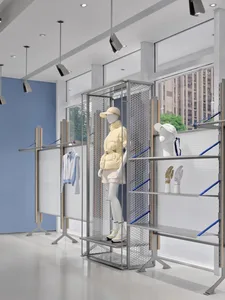 Two mannequins in a white-themed store display, dressed in various clothing items, behind a metal rack