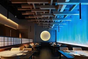 Empty restaurant interior with a large dining table and blue and white walls, creating a modern and inviting atmosphere