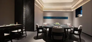 A restaurant dining area with a large wooden table surrounded by chairs, ready to welcome guests