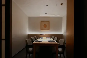 A well-lit and inviting restaurant dining area with a long wooden table surrounded by multiple chairs, creating a calm atmosphere for guests to enjoy their meals