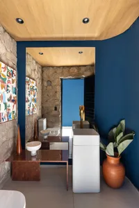 Modern bathroom with a blue accent wall, stone countertop, and two sinks, one on each side, with a toilet nearby