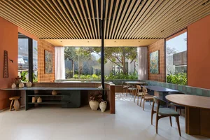 Open living area with a dining table, wooden floors, and walls, surrounded by vases and natural light from windows