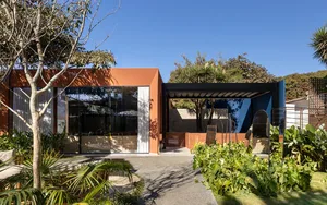 A modern house with a wooden deck in front, featuring a mix of wood and concrete elements, set against a natural background