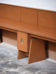 A minimalist interior space featuring a wooden bench in front of a brown wall, with a simple and elegant design