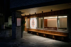 A restaurant with wooden benches and tables in front of large windows, allowing natural light to enter and creating a bright and welcoming atmosphere