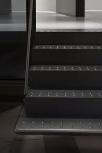 A modern metal staircase with a sleek and contemporary design, set against a dark background