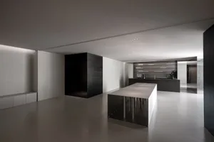 Empty modern kitchen with white walls and floors, featuring a dining table, chairs, and a sink