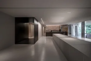 Empty modern kitchen dining space with a large white countertop, two doors, and a dining table near the right wall