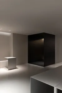 Dimly lit room with a black doorway, two white tables, and a mysterious atmosphere
