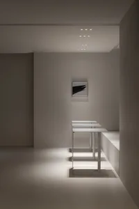Empty modern room with white walls and floors, featuring three metal tables in a clean and minimalist design