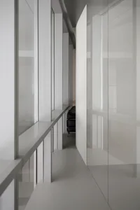 Empty living area with white walls, a glass door, and a couch, chairs, and neutral colors creating a calm and inviting atmosphere