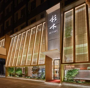 Modern Asian restaurant with a red carpet, potted plants, and warm lighting