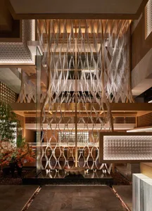 Modern interior design with a large glass wall featuring a white lattice pattern, chairs, and potted plants, creating a sense of openness and inviting atmosphere