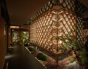 Modern interior space with a wooden honeycomb-patterned wall dividing two rooms, creating a warm and characterful environment
