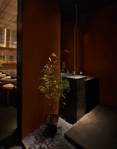 現代餐廳內部，黑石英石檯面、椅子、盆栽與酒瓶，營造時尚氛圍