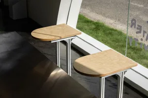 Two wooden stools placed next to a window with natural light, on a metal stand, adding an industrial touch