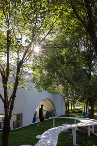 A serene scene of a modern building with a large window, surrounded by trees, and a person standing nearby, conveying a sense of tranquility and appreciation for nature and architecture