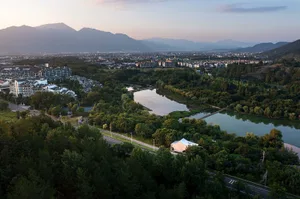 A serene cityscape with a large body of water in front of a building, surrounded by multiple structures with a calm atmosphere