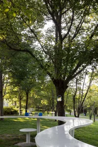 A patio area with a wooden table and metal chairs, surrounded by a park setting, creating a relaxing atmosphere
