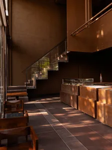 A warm and inviting dining area with a large wooden table surrounded by chairs, stairs leading up to the next floor in the background
