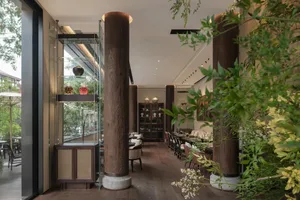 Warm and inviting restaurant interior with wooden columns, dining tables, and chairs, featuring vases and a focus on wood as the primary material