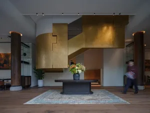Warm and inviting open space with wooden floors and walls, featuring a vase on a table and two people in the scene