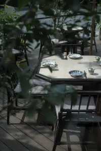 Casual outdoor dining area with wooden tables and chairs, featuring bowls for serving food in a relaxed environment