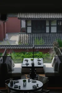Cozy Asian restaurant with a large dining table, red wall, and tiled roof, set up for a meal