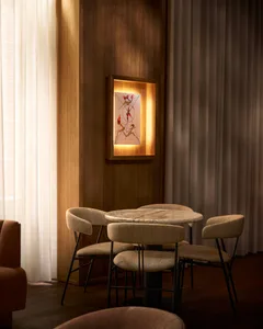 A modern living space with a dining table, chairs, a couch, and a painting, featuring a cozy atmosphere and clean lines