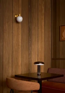 A warm and inviting dining area with a wooden table, chairs, and a lamp, set in a restaurant