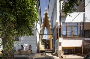 A modern building with a triangular shape, surrounded by people sitting on benches, enjoying the view and each other's company