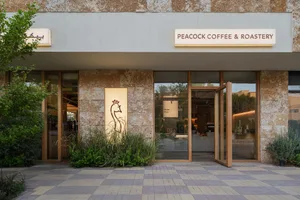 Exterior view of a modern coffee shop with a brick facade, large glass doors, and potted plants