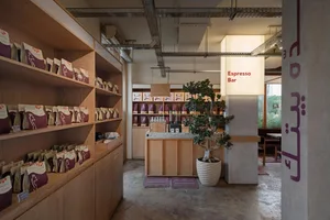 A cozy coffee shop interior with a counter, potted plant, and scattered cups, inviting atmosphere and comfortable seating