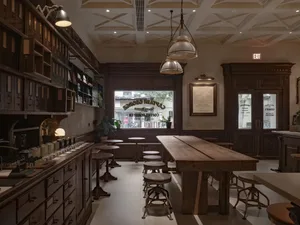A warm and inviting bar area with a wooden table, chairs, and potted plants