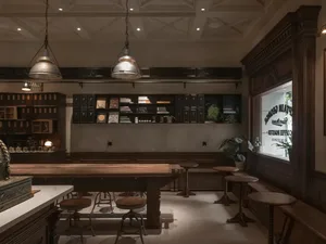 Modern bar area with wooden floors, white walls, black cabinets, and comfortable seating, featuring books on shelves and a cozy atmosphere