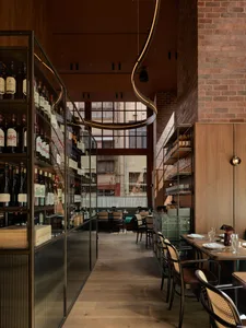 Elegant restaurant interior with a dining area, bar, and wine bottles, featuring a sophisticated atmosphere and comfortable seating