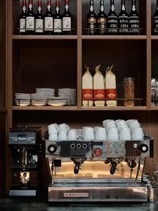 A well-equipped kitchen with a coffee maker, cups, and bottles, set against a neutral background