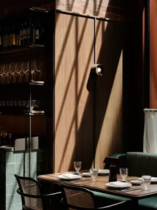 Cozy restaurant dining area with a wooden table, chairs, wine glasses, and bottles, providing a comfortable atmosphere for guests