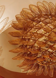 A modern gallery space featuring an arrangement of wooden baskets in various sizes and shapes, with a focus on light and shadow created by the hanging baskets
