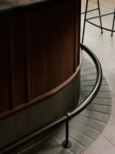 A wooden staircase with a metal railing in a well-lit stairwell, possibly with natural light from windows or glass doors at the top