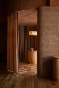 A bathroom with a large wooden tub as the focal point, surrounded by curtains and a warm atmosphere