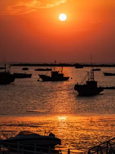 A serene sunset scene with several boats floating on a body of water, evoking a sense of tranquility and relaxation