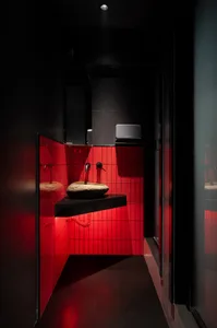 Bathroom with red tile walls and floors, featuring two sinks and mirrors above, giving a modern and sleek appearance