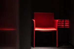 A dark room with a red leather chair as the focal point, suggesting a cozy and intimate dining area setting