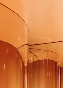 Warm and inviting orange hallway with curved walls, gold accents, and overhead lighting