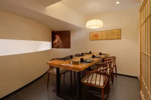 A warm and inviting restaurant dining area with a large wooden table and multiple chairs set for a meal